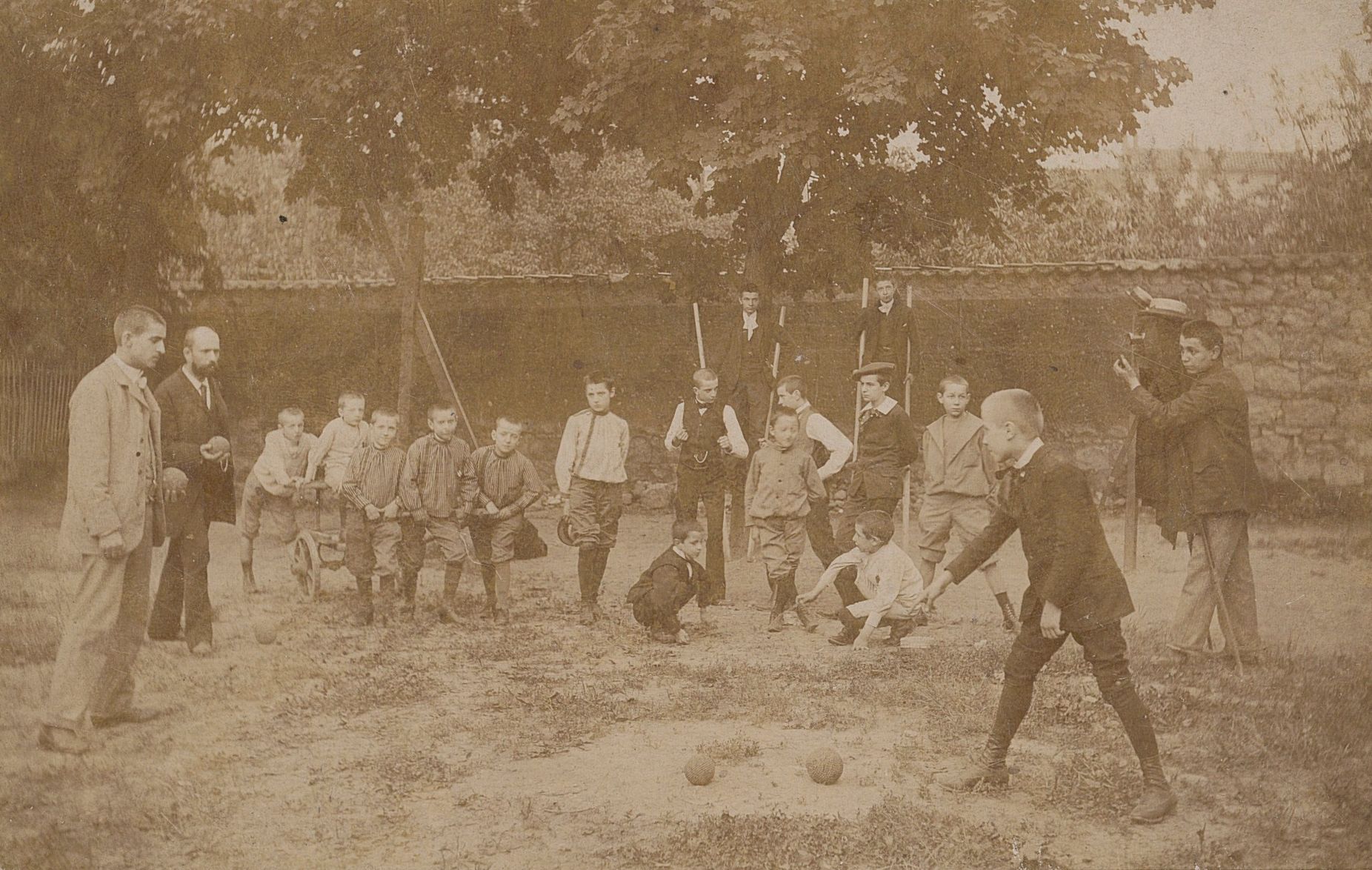 Scène de jeux de boules lyonnaises dans un jardin sous le regard des pensionnaires de l'institution Vismara : photographie NB (1892, cote 100PH/1/130)