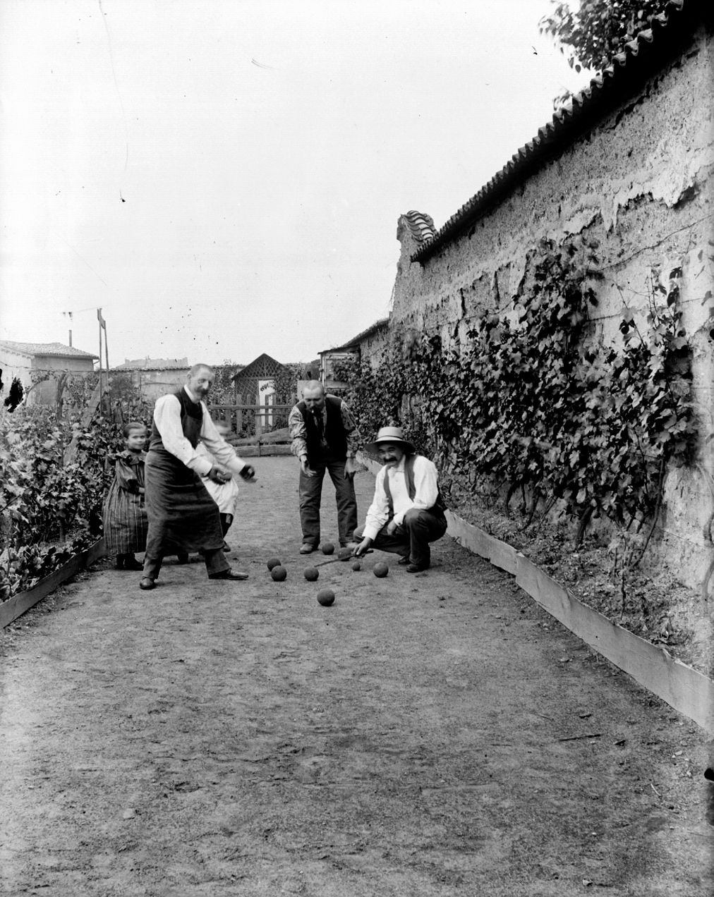 Trois hommes jouant aux boules dans un jardin avec deux enfants : photographie négative NB sur verre (vers 1900, cote 10PH/265)